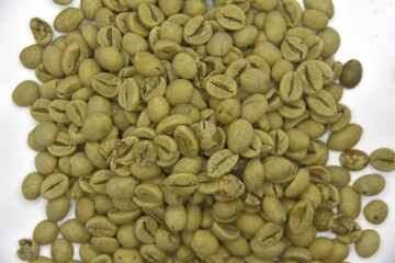 Up close you can see raw coffee beans on a white background