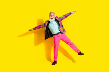 Full size photo of positive classy man stand one legs arms wings wear bright outfit isolated on yellow color background