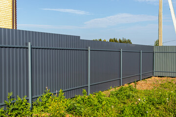 Obraz premium Primed gray side of the profiled sheet. Corrugated board fence. A fence on country plot