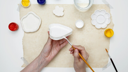 A woman paints clay products. Hobby clay modeling