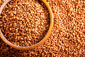 Wooden bowl full of raw wholegrain buckwheat groats