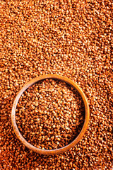 Wooden bowl full of raw wholegrain buckwheat groats