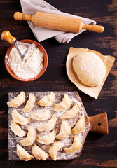 Raw dumplings varenik - traditional Ukrainian food - on wooden board close up.