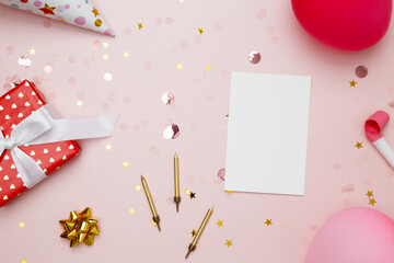 Blank card surrounded by colorful balloons, party hats, candles, and confetti. Concept of festive birthday celebrations