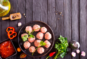 Fresh raw beef meatballs with spices and tomato sauce