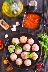 Fresh raw beef meatballs with spices and tomato sauce