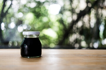 Coffee in a mini glass bottle. Black coffee in glass jar on wood table