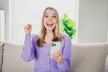 Photo of lovely cheerful girl sit couch winning hold device excited dressed violet garment spend...