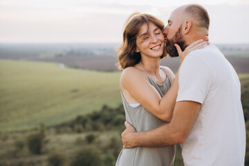 Romantic Couple Embracing in a Scenic Countryside Setting Against a Softly Lit Sky