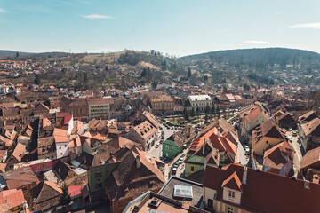 Fototapeta premium The picturesque village showcases a patchwork of terracotta roofs and colorful buildings, surrounded by rolling hills and vibrant greenery, capturing the essence of tranquil rural life