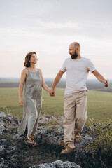 Couple Walking Hand in Hand on Scenic Hillside During a Serene Evening Stroll