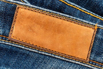 Empty worn leather patch on blue jeans. Empty space for writing. Blank leather jeans label