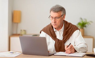 No Ageism. Elderly Businessman Using Laptop And Taking Notes Working Sitting In Modern Office. Selective Focus