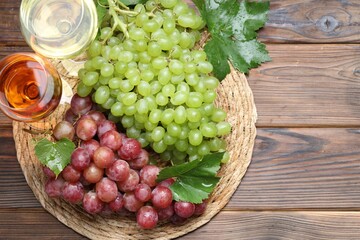 Fresh ripe grapes and glasses of wine on wooden table, flat lay