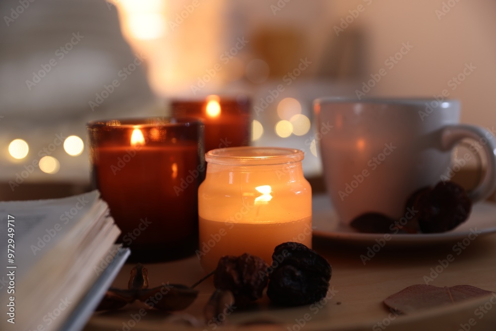 Wall mural Burning candles, cup of drink and decor on tray indoors, closeup. Autumn atmosphere