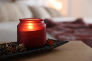 Burning candle and dry flowers on wooden table indoors, closeup. Autumn atmosphere