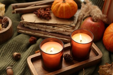 Burning candles, old books and autumn decor on green sweater