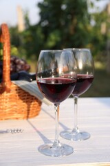 Tasty wine in glasses on white wooden table outdoors