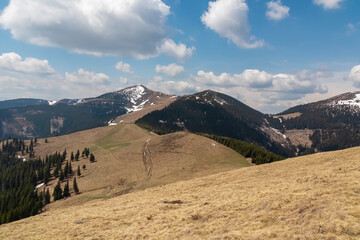 Scenic hiking trail over dry alpine meadows and rolling hills to snow-capped mountain peak Lenzmoarkogel, Gleinalpe, Lavantal Alps, Styria, Austria. Wanderlust in wilderness of Austrian Alps in spring