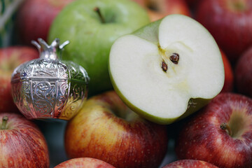 Freshly picked red and green apples surrounded by a decorative silver pomegranate. Rosh hashanah, jewish New Year holiday concept, background. The centerpiece is a beautifully silver pomegranate