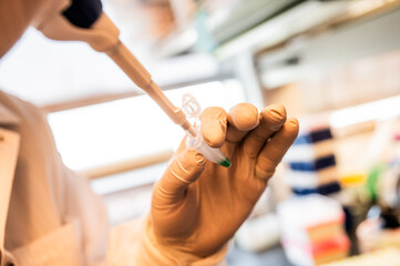 Filling a test tube with chemicals in a lab with white gloves