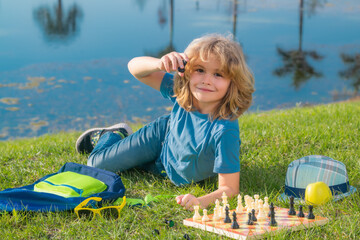 Chess game for kids. Child playing chess outdoor in park.