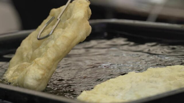 Fried flatbread (L&aacute;ngos in Hungarian language) frying in oil.