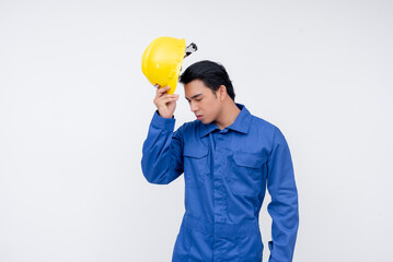 A young asian seaman or construction worker in blue coveralls removes his safety helmet after a...