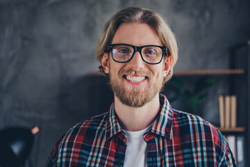 Photo of young male look camera toothy smile wear plaid shirt comfortable modern office loft room interior indoors businessman workspace