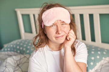 Woman with sleep mask feeling tired in bed - morning routine and self-care concept