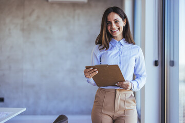 Confident Businesswoman Holding Clipboard in Modern Office Setting