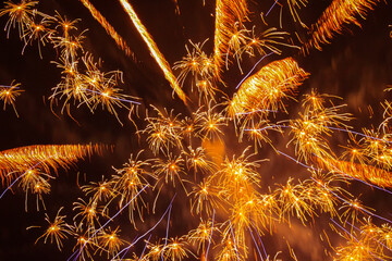 The explosion of fireworks that produces beautiful colorful lights in the dark sky. New Year's Eve celebration moment