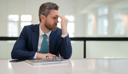 Tired man having a terrible headache. Exhausted man feeling unhealthy, upset about headache illness. Stressed middle-aged man having headache. Migraine and headache concept.