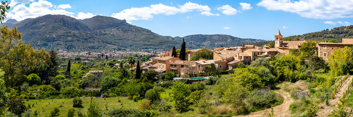 Panoramic view over the quaint village Biniaraix, framed by the lush valley of Sóller and Serra de Tramuntana mountains on a sunny day, ideal for promoting Mallorca as a tranquil travel destination.