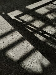 Shadow and light on concrete floor. Abstract background. Indoor railing of staircase. Closeup detail of material. Urban design. Stone and metal structure. Contrast art. Minimalistic design of exterior
