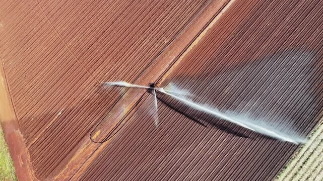 farm irrigator watering ploughed red dirt paddock field, farming agriculture agricultural equipment, water use conservation environment