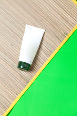 Straw mat with jar of facial cream on green background. Summer concept. Face cream concept. space for text.