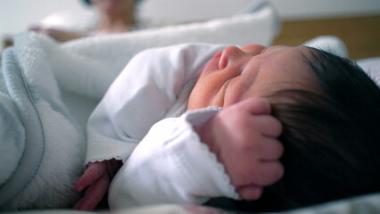Newborn baby resting on a bed, peacefully lying on their side with a hand near their face. a tender moment of sleep, comfort, and early life in a warm, secure environment