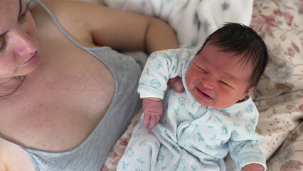 Mother gently cradling her newborn baby, who appears to be crying. Emotional moment showcasing...