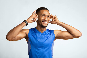 Active Lifestyle. Portrait of black man with perfect muscular body listening to music during training, yellow wall