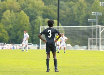 Black kid plays soccer against white kids.