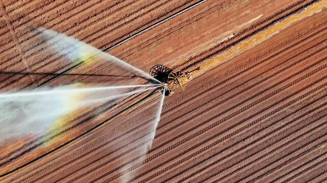 farm irrigator watering ploughed red dirt paddock field, farming agriculture agricultural equipment, water use conservation environment