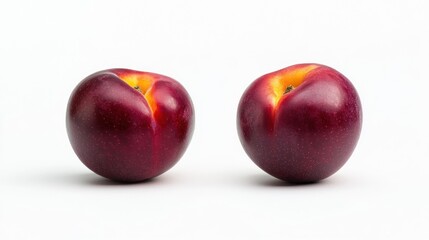 Fototapeta premium Two shiny red plums on a white background, showcasing their vibrant color and smooth texture.