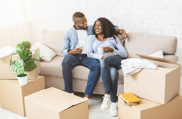 Place together. Happy bblack couple taking break, drinking tea, unpacking on moving day, copy space