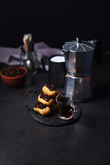Chocolate eclairs with a cup of coffee and a coffee pot	