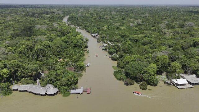 Drone flies from Guam&aacute; River down Igarap&eacute; do Combu, following red speedboat going through the forested island south of Bel&eacute;m, Par&aacute;, Brazil