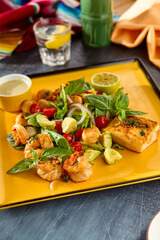 Gourmet Seafood Platter Shrimp, Scallops, Fish, and Fresh Greens with Avocado and Cherry Tomatoes on Vibrant Yellow Plate