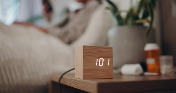 Clock, digital and night with person in bedroom of home for break, rest or sleep on weekend evening. Alarm, relax and time with bedside table in apartment for hospitality, peace or quiet in dark