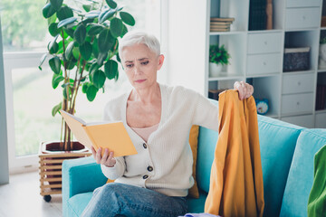 Photo of charming lovely senior woman dressed white cardigan hold planner dirty jumper read home cleaning tasks indoors