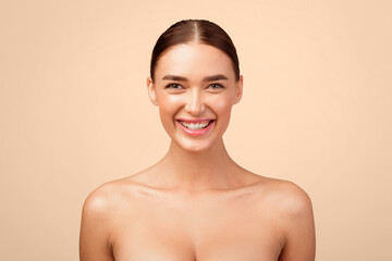 Portrait Of Cheerful Young Lady Smiling Looking At Camera Posing Shirtless In Studio Standing Over Gray Background. Headshot Of Gorgeous Naked Woman Expressing Positive Emotions. Natural Female Beauty